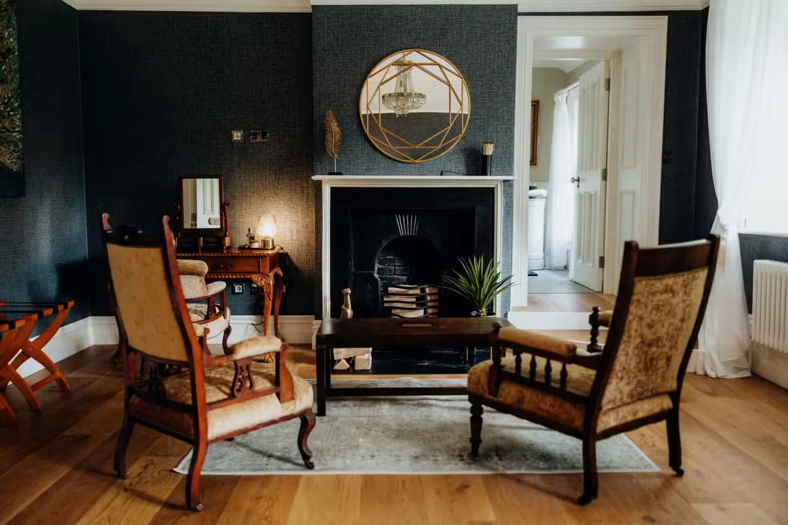 A quiet sitting room at Bettystown House with armchairs beside the fireplace